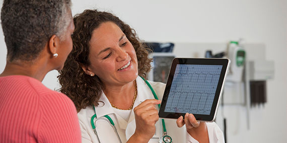 A doctor shows a patient test results on a digital tablet