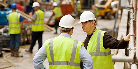 Construction workers on a job site wearing hard hats and safety vests