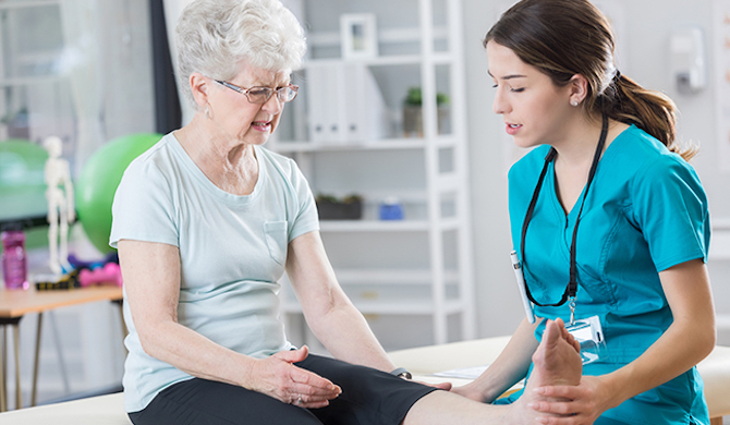 Physiotherapist examining elder female's leg